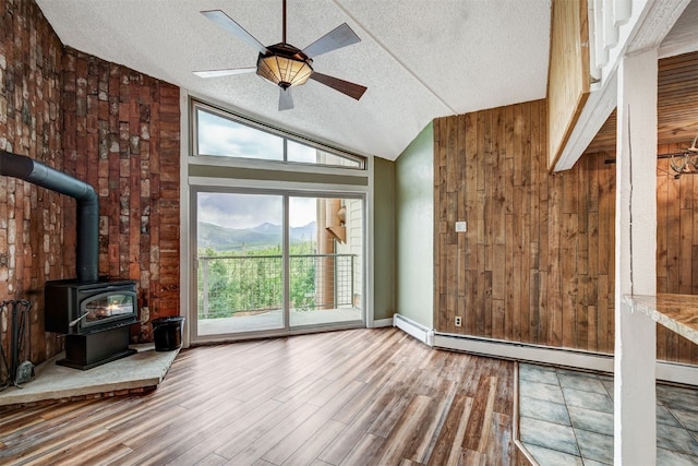 7031 Ryan Gulch Rd Unit 301, Silverthorne, CO 80498 - unfurnished living room with a textured ceiling, a wood stove, wood finished floors, ceiling fan, and vaulted ceiling