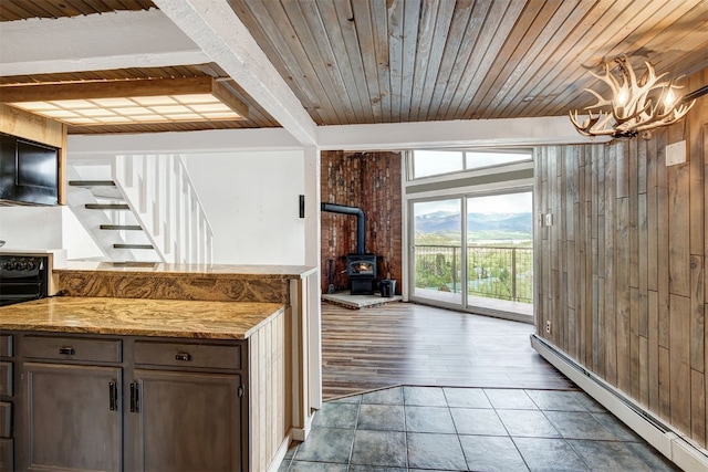 7031 Ryan Gulch Rd Unit 301, Silverthorne, CO 80498 - kitchen with a baseboard heating unit, a wood stove, a wooden ceiling with exposed beams, a chandelier, and tile patterned flooring