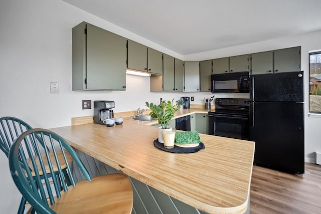 9876 Ryan Gulch Rd Unit 206, Silverthorne, CO 80498 - kitchen featuring black appliances, a peninsula, wood finished floors, light countertops, and a kitchen bar
