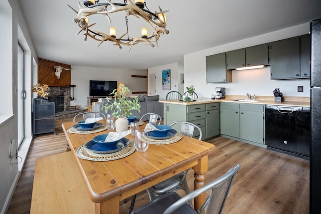 9876 Ryan Gulch Rd Unit 206, Silverthorne, CO 80498 - dining area featuring a chandelier, light wood-style flooring, and a stone fireplace