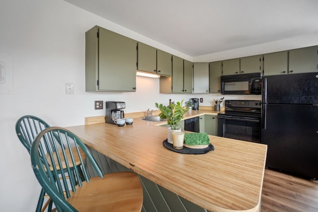 9876 Ryan Gulch Rd Unit 206, Silverthorne, CO 80498 - kitchen with black appliances, a peninsula, a sink, wood finished floors, and green cabinets