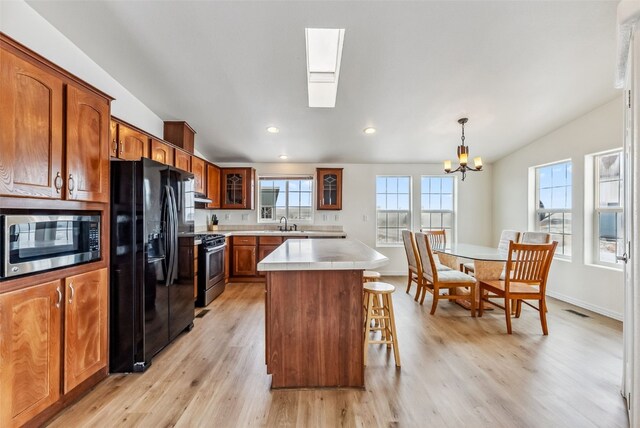 370 Stone Creek Dr, Fairplay, CO 80440 - kitchen with appliances with stainless steel finishes, a breakfast bar area, brown cabinetry, glass insert cabinets, and lofted ceiling with skylight