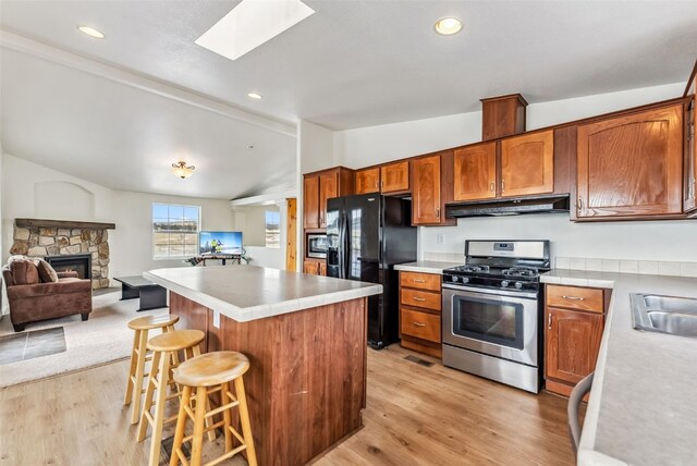 370 Stone Creek Dr, Fairplay, CO 80440 - kitchen with light countertops, lofted ceiling with skylight, under cabinet range hood, light wood-style floors, and stainless steel appliances
