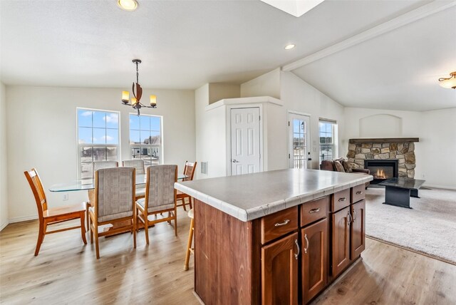 370 Stone Creek Dr, Fairplay, CO 80440 - kitchen with a kitchen island, a fireplace, vaulted ceiling, a chandelier, and light wood-style flooring