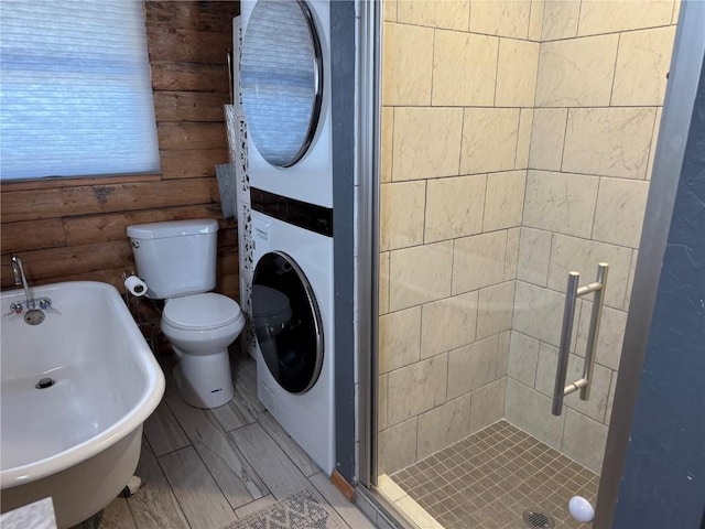 bathroom featuring tiled shower, toilet, and stacked washer / dryer