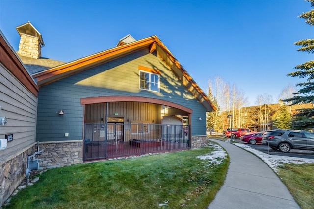 view of home's exterior featuring stone siding and a lawn