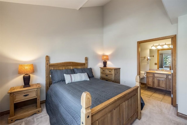 bedroom with a sink, light tile patterned flooring, ensuite bathroom, light colored carpet, and high vaulted ceiling