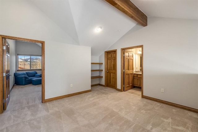 unfurnished bedroom with beamed ceiling, baseboards, light carpet, and connected bathroom