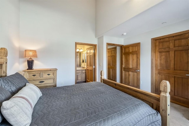 bedroom featuring ensuite bath, a towering ceiling, and carpet floors