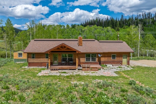 27100 Beaver Canyon Dr, Clark, CO 80428 - back of house featuring a view of trees, a deck, a chimney, a yard, and roof with shingles