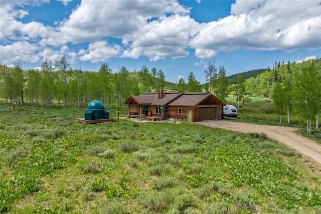 27100 Beaver Canyon Dr, Clark, CO 80428 - view of front facade featuring dirt driveway, a chimney, an attached garage, and a view of trees