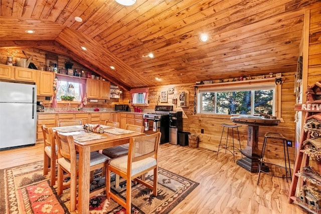 dining room with recessed lighting, vaulted ceiling, a wealth of natural light, and wood walls