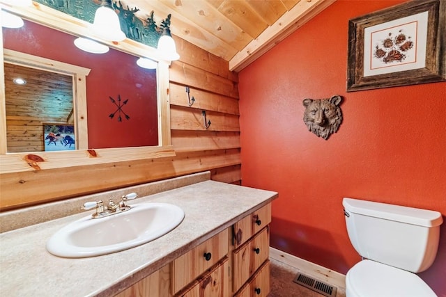 bathroom with wood walls, vaulted ceiling, visible vents, vanity, and wood ceiling