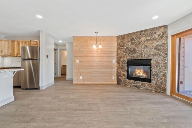 unfurnished living room with light wood-type flooring, baseboards, a fireplace, and recessed lighting