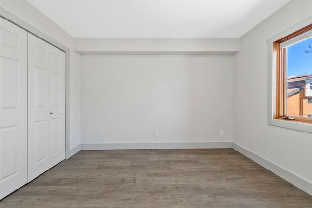 unfurnished bedroom with baseboards, wood finished floors, and a closet