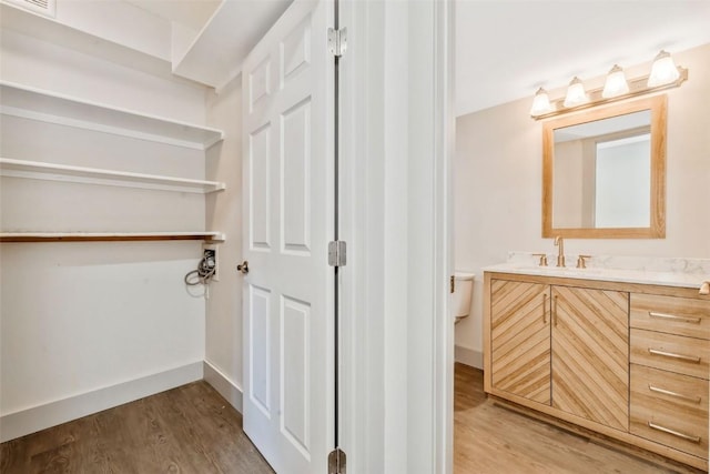 bathroom featuring baseboards, wood finished floors, toilet, and vanity