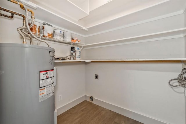 washroom with electric water heater, baseboards, wood finished floors, electric dryer hookup, and laundry area