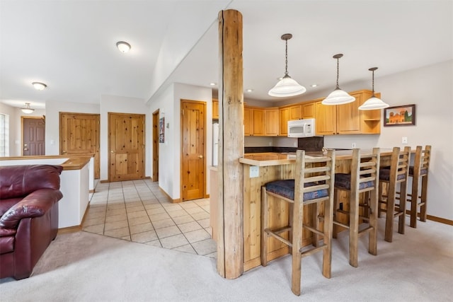 129 Lookout Ridge Dr Unit 129, Dillon, CO 80435 - kitchen featuring white microwave, light colored carpet, a breakfast bar area, recessed lighting, and hanging light fixtures