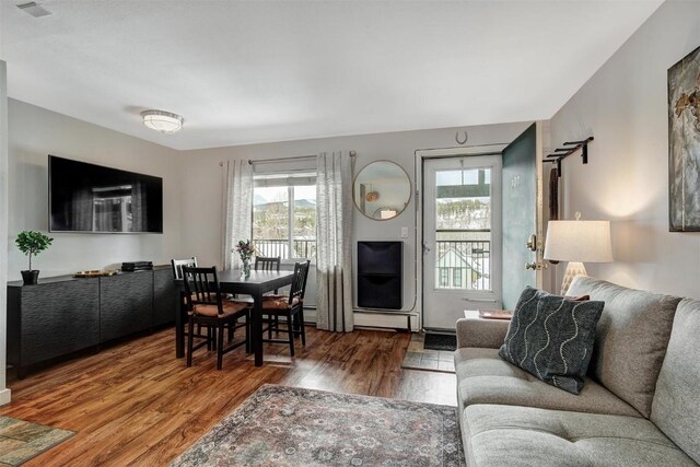 living area with wood finished floors, visible vents, and baseboard heating