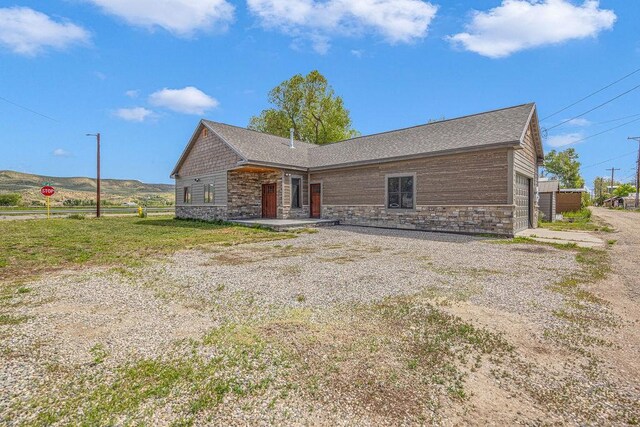 527 E Lincoln Ave, Hayden, CO 81639 - view of front of property with stone siding, an attached garage, and a shingled roof