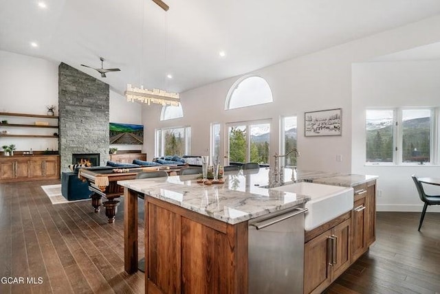 671 Vasquez Rd, Winter Park, CO 80482 - kitchen with stainless steel dishwasher, a sink, a kitchen island with sink, a fireplace, and dark wood-style flooring