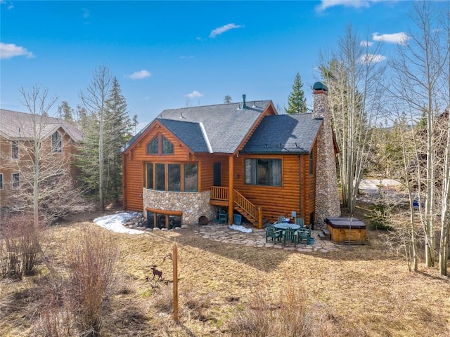 105 Windflower Ln, Frisco, CO 80443 - rear view of house with a hot tub, stone siding, roof with shingles, a chimney, and a patio area