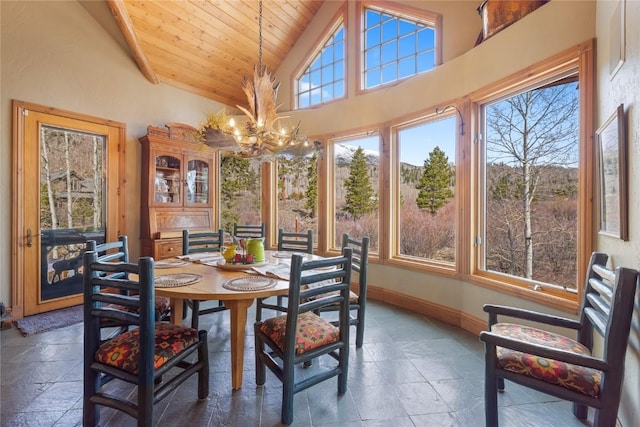 dining room featuring a chandelier, stone tile floors, wood ceiling, baseboards, and high vaulted ceiling