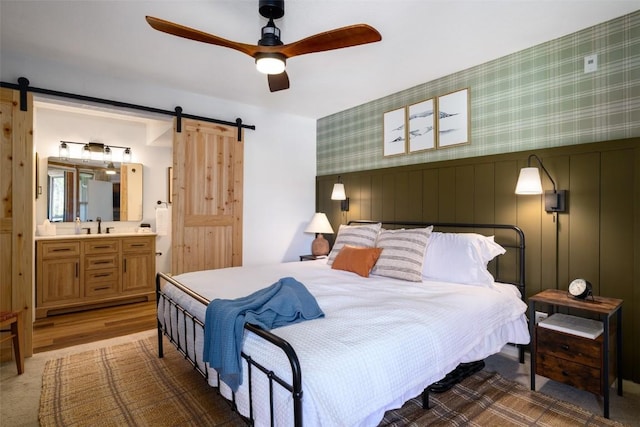 2700 Village Dr Unit D203, Steamboat Springs, CO 80487 - bedroom featuring a barn door, wallpapered walls, ensuite bathroom, and ceiling fan