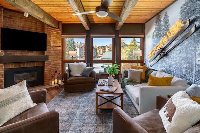 2700 Village Dr Unit D203, Steamboat Springs, CO 80487 - living area featuring wood ceiling, a ceiling fan, wood finished floors, beamed ceiling, and a fireplace