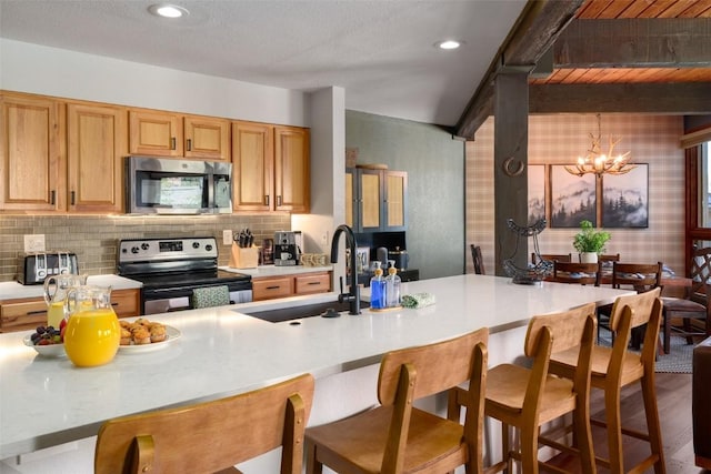 2700 Village Dr Unit D203, Steamboat Springs, CO 80487 - kitchen with appliances with stainless steel finishes, a sink, light countertops, a kitchen breakfast bar, and backsplash