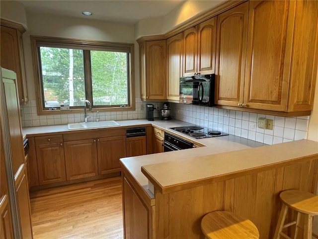 2300 Apres Ski Way Unit 12, Steamboat Springs, CO 80487 - kitchen with a sink, black appliances, a peninsula, light wood finished floors, and plenty of natural light