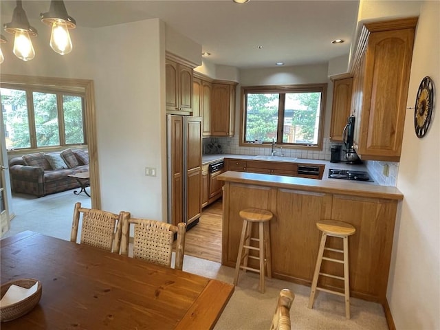 2300 Apres Ski Way Unit 12, Steamboat Springs, CO 80487 - kitchen featuring a sink, a peninsula, backsplash, black appliances, and light countertops