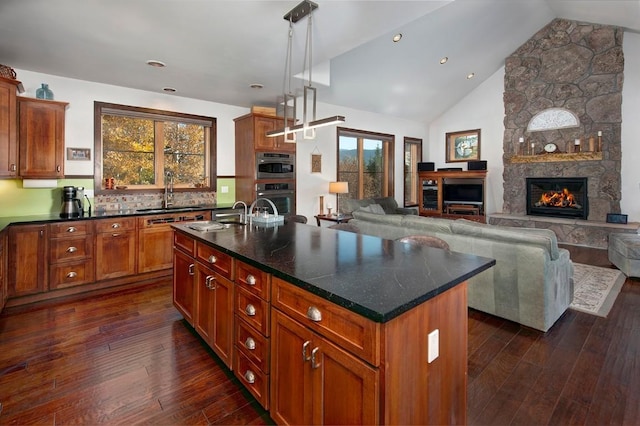 27 Habitat Ct, Dillon, CO 80435 - kitchen with dark wood-type flooring, a stone fireplace, a kitchen island with sink, open floor plan, and a sink