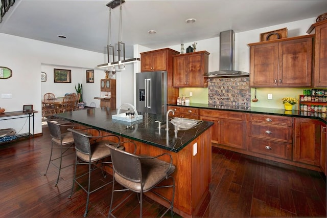 27 Habitat Ct, Dillon, CO 80435 - kitchen featuring wall chimney exhaust hood, high quality fridge, a sink, a breakfast bar area, and gas cooktop