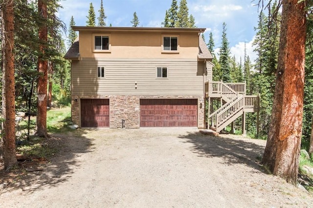 554 Lakeview Dr, Breckenridge, CO 80424 - view of front of house featuring an attached garage, driveway, stone siding, stairway, and stucco siding