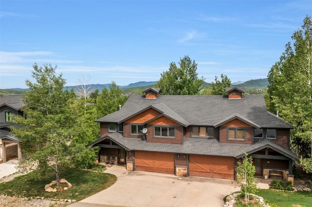 1250 Harwig Cir, Steamboat Springs, CO 80487 - view of front of house featuring an attached garage, concrete driveway, a mountain view, roof with shingles, and stone siding