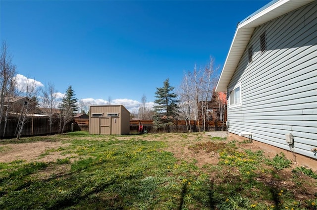 view of yard featuring a storage unit, a fenced backyard, and an outbuilding