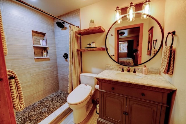 bathroom featuring vanity, toilet, tiled shower, connected bathroom, and a chandelier