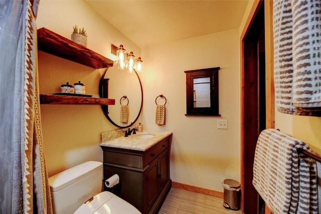bathroom with toilet, baseboards, and vanity