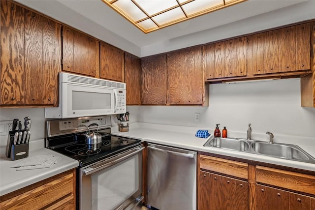 kitchen featuring light countertops, brown cabinetry, stainless steel appliances, and a sink