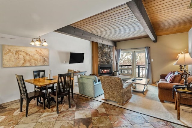 living area with an inviting chandelier, stone finish floor, a large fireplace, and beamed ceiling