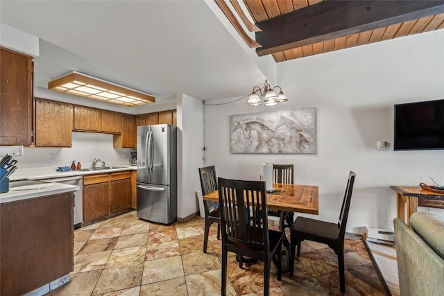 kitchen with baseboard heating, brown cabinets, light countertops, stone finish flooring, and freestanding refrigerator