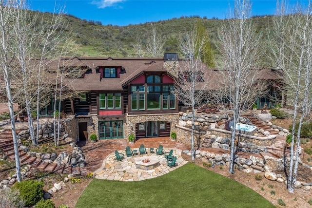 32855 More Ln, Steamboat Springs, CO 80487 - back of house featuring an outdoor fire pit, stone siding, a patio area, and a lawn