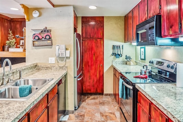 kitchen featuring baseboards, reddish brown cabinets, stainless steel appliances, and a sink