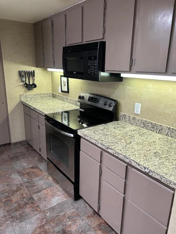 22340 US Highway 6 Unit 1788, Keystone, CO 80435 - kitchen featuring electric stove, black microwave, light stone finish floors, light stone counters, and a textured wall