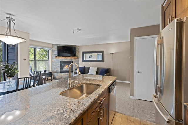 100 S Park Ave Unit E321, Breckenridge, CO 80424 - kitchen featuring appliances with stainless steel finishes, open floor plan, a stone fireplace, brown cabinetry, and light stone countertops