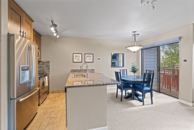 100 S Park Ave Unit E321, Breckenridge, CO 80424 - kitchen featuring appliances with stainless steel finishes, brown cabinetry, a peninsula, backsplash, and dark stone countertops