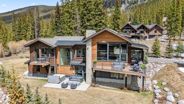 427 Whispering Pines Cir, Blue River, CO 80424 - back of house with a standing seam roof, a forest view, metal roof, and an outdoor living space