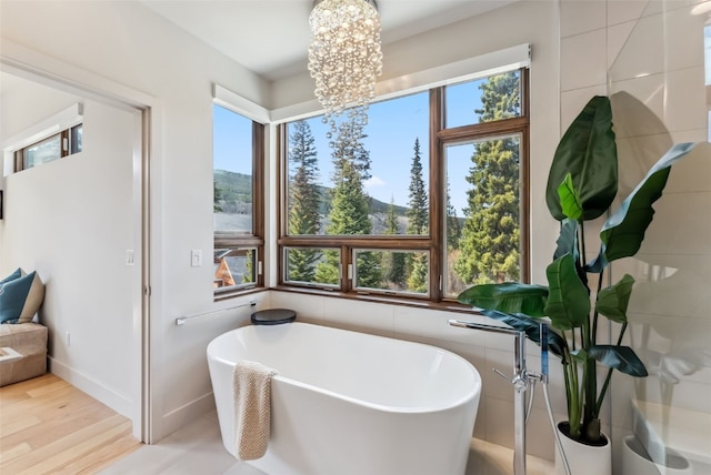 427 Whispering Pines Cir, Blue River, CO 80424 - full bath featuring a freestanding bath, a chandelier, a mountain view, baseboards, and wood finished floors