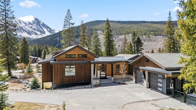 427 Whispering Pines Cir, Blue River, CO 80424 - view of front of home with covered porch, asphalt driveway, a mountain view, a garage, and a wooded view